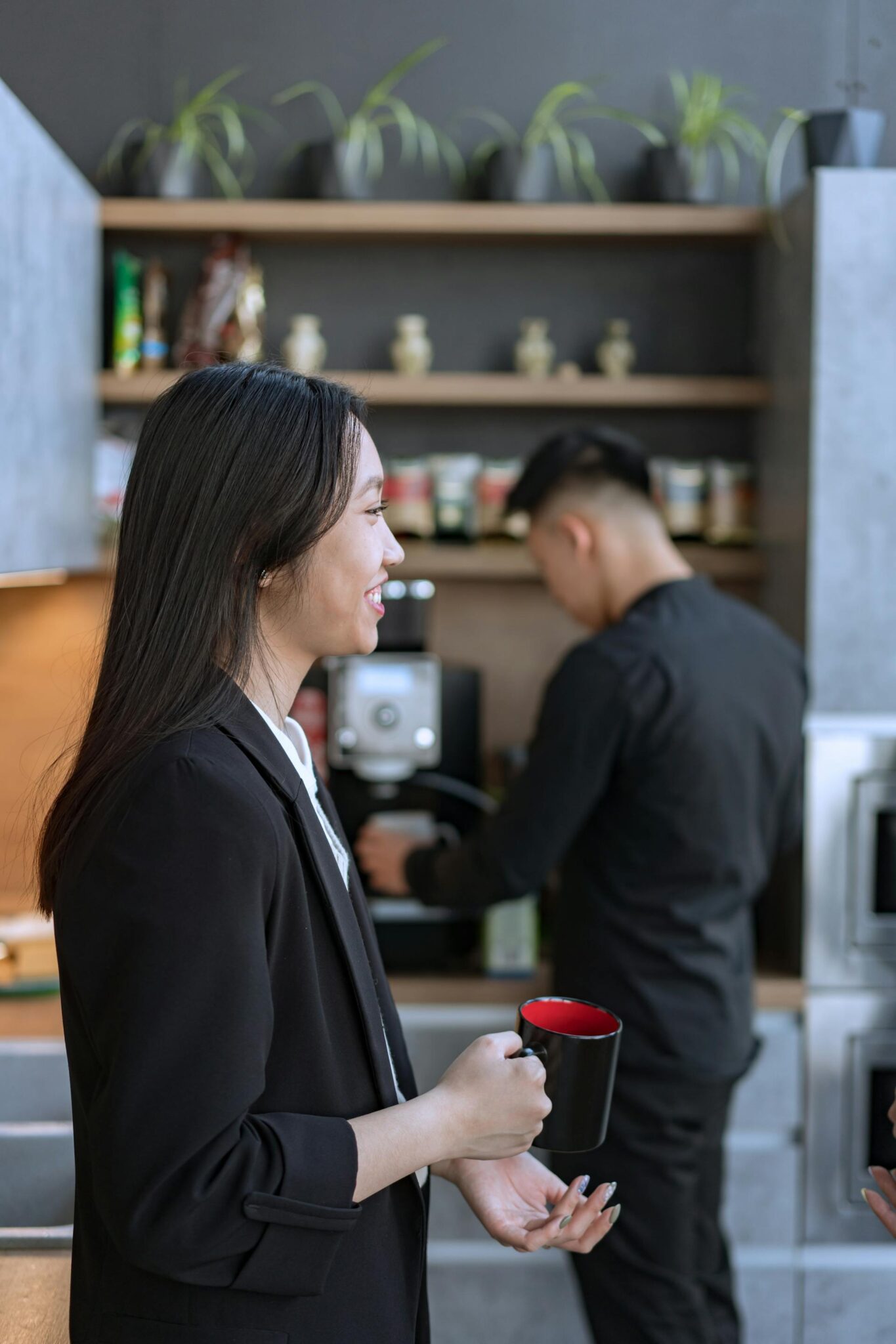 Modernus kavos aparatas šviesiame biure ant stalo šalia šviežios kavos puodelio.